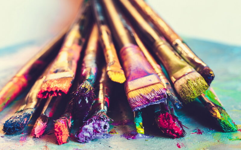 Artist paintbrushes with paint closeup on artistic canvas. Retro toned. Selective focus.